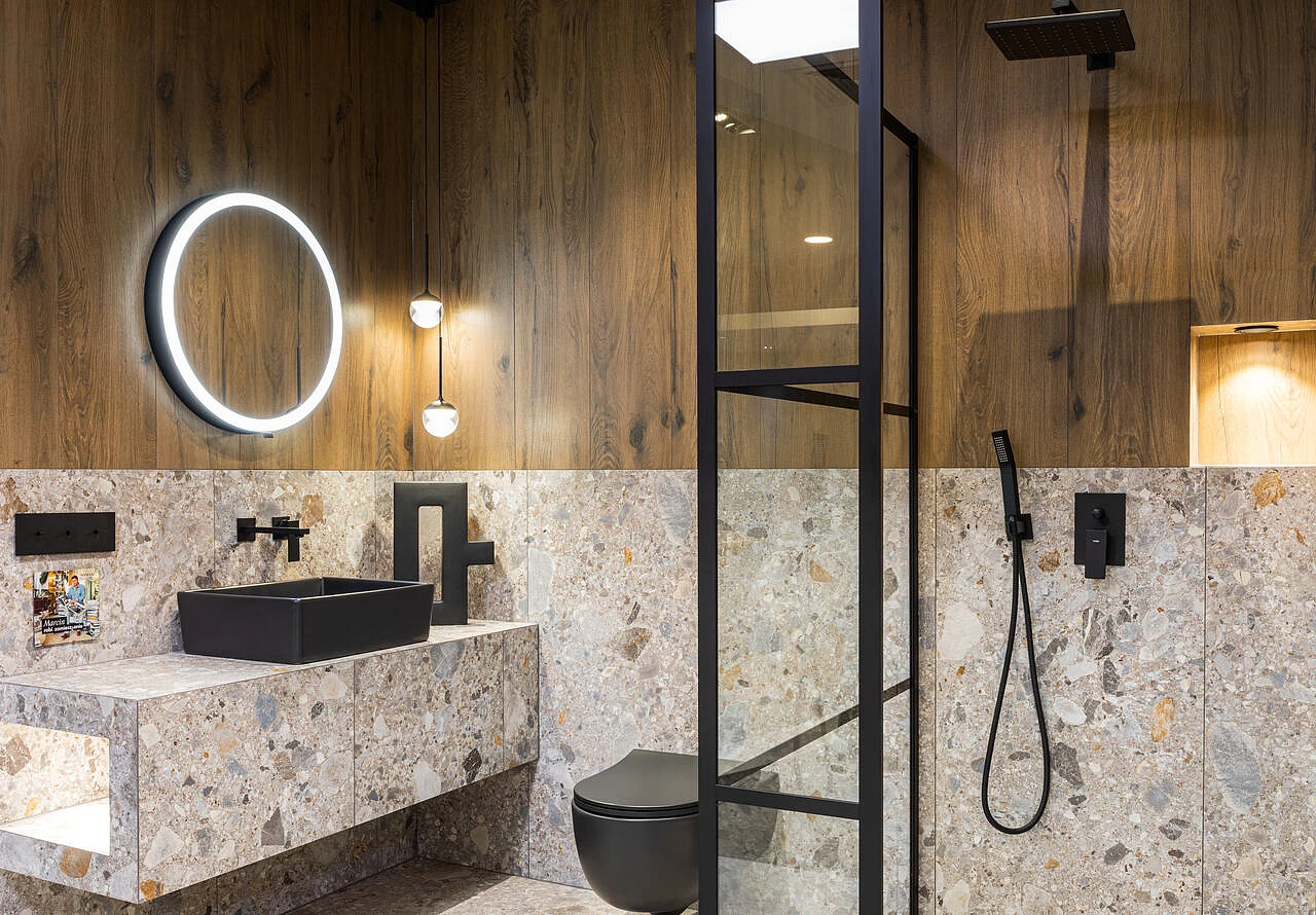 Aranżacja łazienki z wykorzystaniem drewnianych paneli oraz jasnych płytek w stylu lastryko w dużym formacie.